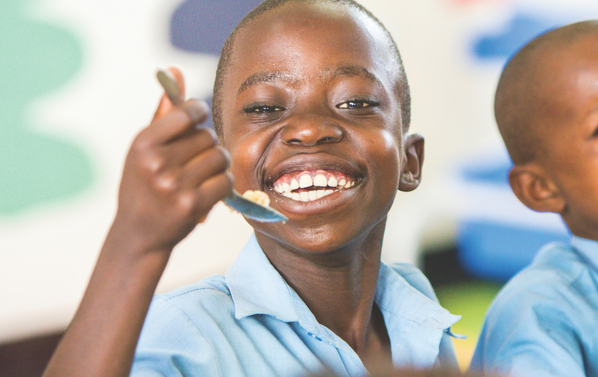 Kid smiling eating a spoonful of rice